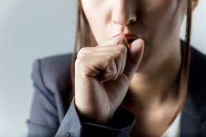 A woman coughs into her hand.