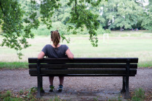 A woman sits on a park bench alone.