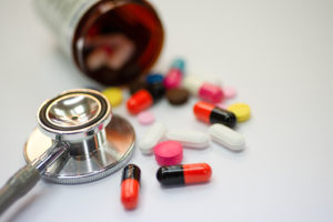 A stethoscope is shown next to a prescription bottle filled with cholesterol medication.