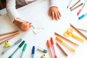 A child draws a picture with different colored pens.