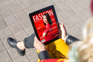 A person holds a "Fashion" magazine in her hand.