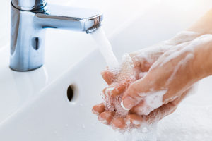 A person washes their hands with soap and hot water for twenty seconds.