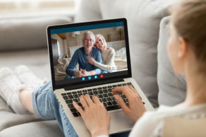 A person sits on the couch and video chats with their loved ones on their laptop.
