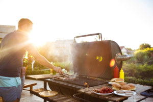 A person is grilling hot dogs and hamburgers.