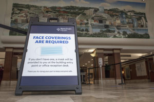 A Spectrum Health sign reads: "Face Coverings Are Required."