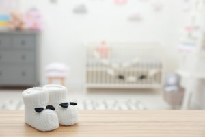 A pair of white baby socks sit on a dresser inside a nursery room.