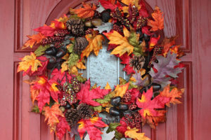 A front door holds a Fall-colored wreath.