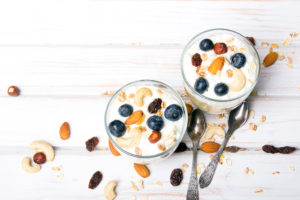Two bowls of a concoction of yogurt, nuts and berries are shown.