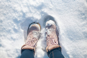 A person wears their snow boots as they walk through the snow outside.