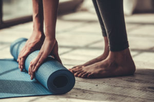 A person unravels their yoga mat for a workout.