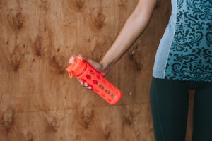 A person holds a red water bottle.