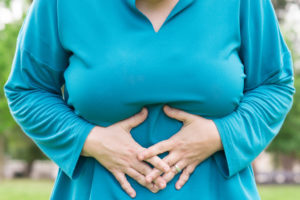 A woman holds her tummy, representing bloating.