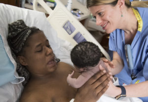 Allison Tran, a certified nurse midwife, hands a newborn baby to their mother.