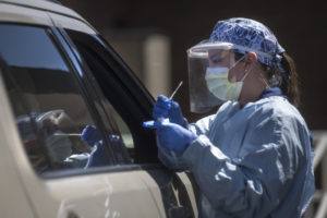 A medical professional jots down information at a drive-through COVID-19 test site.